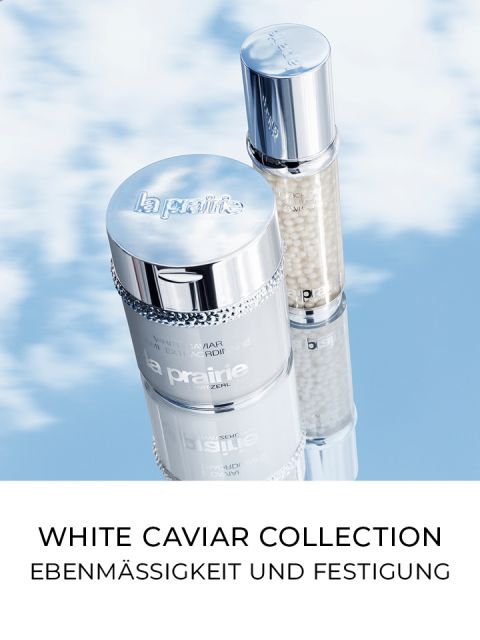 Zwei Hautpflegeprodukte aus der White Caviar Collection von La Prairie werden vor einem bewölkten blauen Himmelshintergrund präsentiert. Der Text darunter lautet „White Caviar Collection: Ebenmäßigkeit und Festigung.