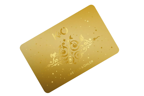 Eine goldene Karte mit dekorativen Schnörkeln und Sternen, auf der in eleganten Buchstaben „K&O“ und „KASTNER & ÖHLER“ aufgedruckt sind. Die Karte hat ein luxuriöses und festliches Design.