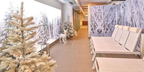 Ein ruhiger, winterlich gestalteter Innenbereich bietet weiße Loungesessel, künstliche schneebedeckte Bäume und einen dekorativen weißen Hirsch. Große frostige Waldwandpaneele verstärken die ruhige Atmosphäre.