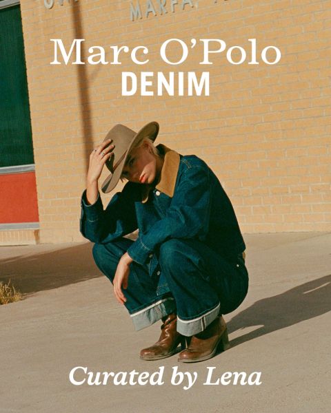 Eine Person, die einen breitkrempigen Hut, eine Jeansjacke und Jeans trägt, hockt im Freien vor einer Backsteinmauer. Der Text auf dem Bild lautet "Marc O'Polo DENIM" und "Kuratiert von Lena".