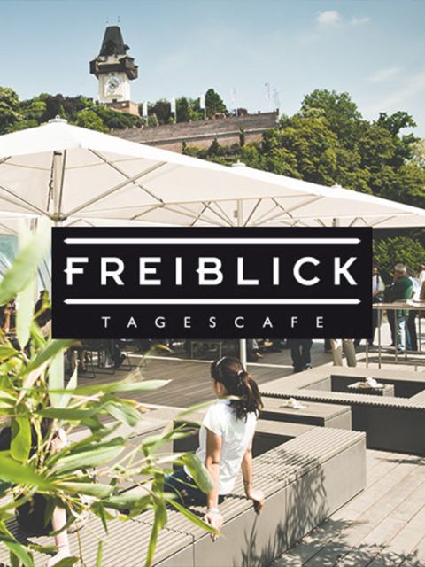 Eine Café-Szene auf dem Dach mit Leuten, die auf Bänken unter Sonnenschirmen entspannen. Ein üppiger grüner Hintergrund und ein historischer Uhrturm sind sichtbar. Der Overlay-Text lautet „FREIBLICK – TAGESCAFE“.