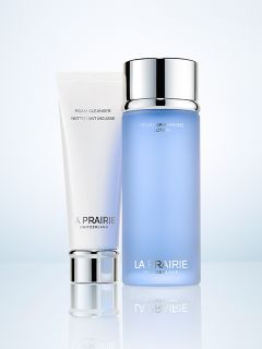 Eine weiße Tube mit La Prairie-Reinigungsschaum und eine blaue Flasche mit La Prairie Cellular Refining Lotion sind nebeneinander vor einem hellen Hintergrund abgebildet.