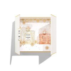 In einer geöffneten weißen Geschenkbox sind zwei Parfümflakons mit der Aufschrift „Coco Mademoiselle Chanel Paris“ zu sehen. Der linke Flakon ist mit einer klaren Flüssigkeit gefüllt, der rechte mit einer rosa Flüssigkeit. Der Hintergrund ist mit einem goldenen Schneeflockenmuster versehen.