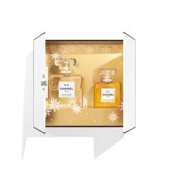 Offene weiße Schachtel mit zwei Flakons des Parfüms Chanel No. 5 auf goldenem Hintergrund mit Schneeflockenmotiven. Die größere Flasche trägt die Aufschrift „Eau de Parfum“, die kleinere die Aufschrift „L'Eau“.