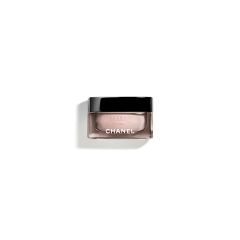 In der Mitte befindet sich ein kleiner Chanel-Make-up-Behälter mit schwarzem Deckel und durchsichtigen Seitenwänden, in dem sich eine zartrosa Creme befindet. Er steht auf einem schlichten weißen Hintergrund.