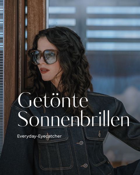 Eine Frau mit gewelltem dunklem Haar, die eine große getönte Sonnenbrille und eine Jeansjacke trägt, steht an einer Holzwand. Der Text lautet: Getönte Sonnenbrillen" und "Everyday-Eyecatcher".
