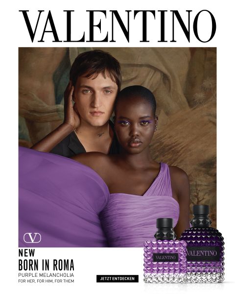 Ein Mann und eine Frau posieren gemeinsam auf Steinstufen. Der Mann trägt einen schwarzen Mantel, die Frau ein auffälliges pinkfarbenes Off-Shoulder-Outfit. Unten rechts sind zwei Valentino-Parfümflaschen zu sehen. Darüber steht „VALENTINO“.