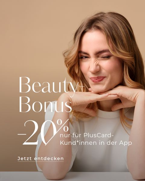 Eine Frau mit langen Haaren zwinkert und stützt ihr Kinn auf ihre Hände vor beigem Hintergrund. Text auf dem Bild lautet: „Beauty Bonus -20 % nur für PlusCard-Kund*innen. Jetzt entdecken.“.