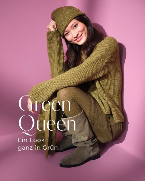 Eine lächelnde Frau sitzt vor einem rosa Hintergrund und trägt einen grünen Strickpullover, eine Mütze, eine Wildlederhose und Stiefel. Der Text lautet: "Grüne Königin. Ein Look ganz in Grün. Jetzt entdecken.