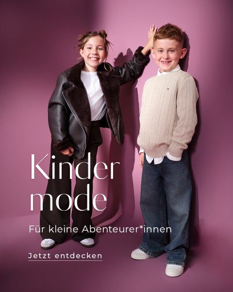 Zwei lächelnde Kinder stehen vor einem rosa Hintergrund. Das Mädchen trägt eine dunkle Jacke und eine Hose, der Junge einen hellen Pullover und eine Jeans. Der deutsche Text wirbt für Kindermode für kleine Abenteurer.