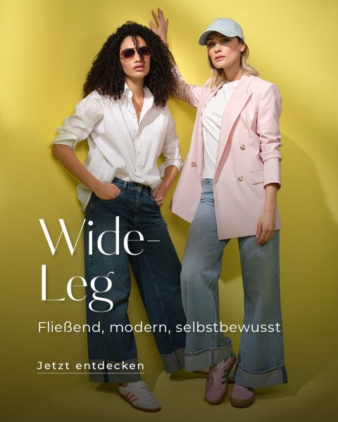 Zwei Frauen posieren vor einem gelben Hintergrund, beide tragen Jeans mit weitem Bein. Die eine trägt ein weißes Shirt mit Sonnenbrille, die andere einen rosa Blazer und eine Mütze. Text: „Wide-Leg: Fließend, modern, selbstbewusst. Jetzt entdecken.