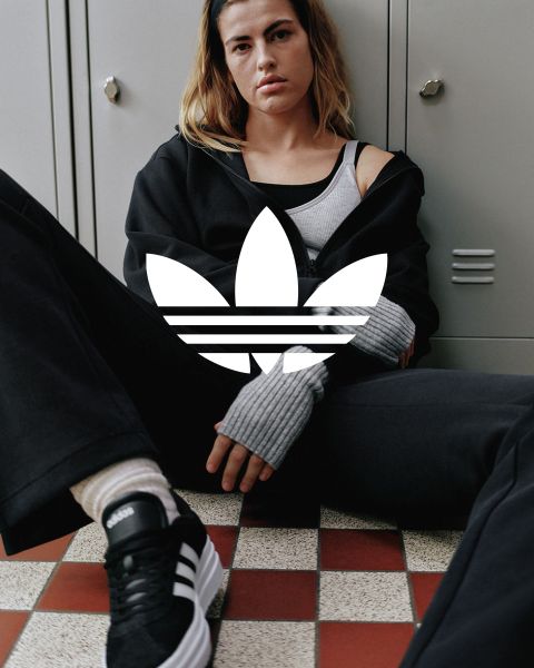 Das Bild zeigt das weiße Adidas-Trefoil-Logo mit drei Blättern und drei horizontalen Streifen, zentriert auf einem einfarbig blauen Hintergrund.