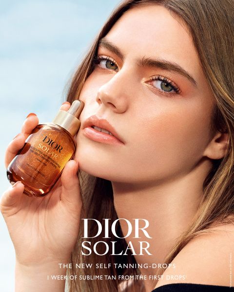 Ein Flakon von Dior Capture Le Sérum, umgeben von rosafarbenen Blütenblättern und zarten Schmetterlingen, darüber das Dior-Logo und der Slogan "Because I Adore You".