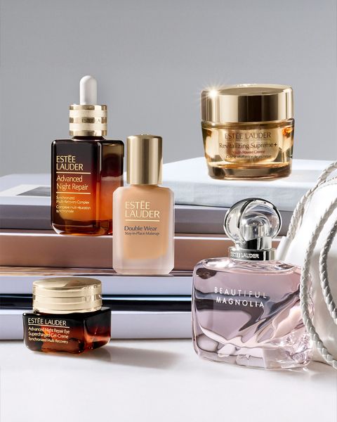 Eine Frau mit langen Haaren posiert mit einer Flasche Estée Lauder Advanced Night Repair im Vordergrund. Im Hintergrund ist eine nächtliche Stadtlandschaft zu sehen. Ein deutscher Text beschreibt die Vorteile des Hautpflegeprodukts.
