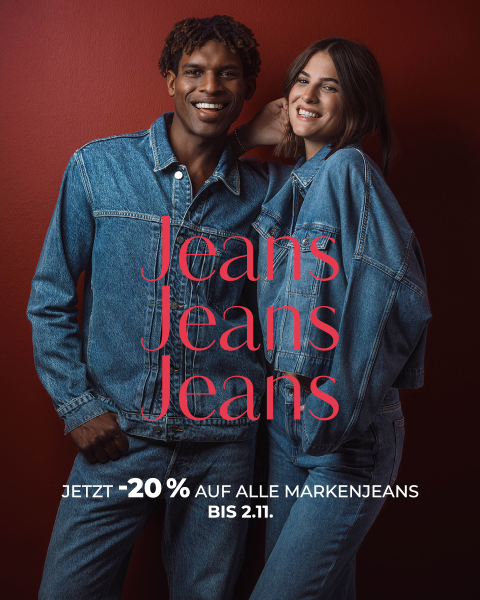 Zwei Personen in Jeansjacken und Jeans lächeln vor einem roten Hintergrund. Text: „Jeans Jeans Jeans. Jetzt -20 % auf alle Markenjeans bis zum 2.11.“.