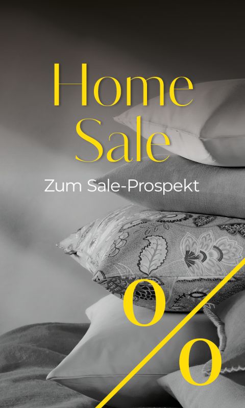 Ein Stapel Kissen in verschiedenen Mustern und Texturen mit der Aufschrift „Home Sale“ und einem großen Prozentzeichen in gelber Schrift.
