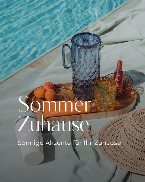 Frau im Badeanzug mit Leopardenmuster liegt am Pool mit Getränken, Sonnencreme und Obst auf einem Tablett. Der Text lautet: "Sommer Zuhause. Sonnige Akzente für Ihr Zuhause.