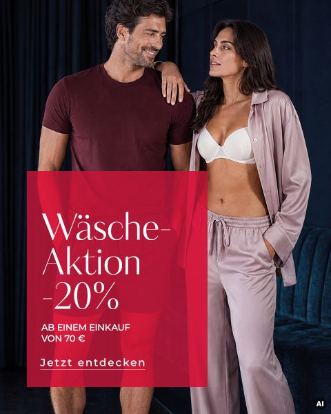 Ein Mann in burgunderrotem Outfit und eine Frau in BH und Satin-Pyjama stehen nebeneinander. Auf einem roten Kasten steht: „Wäsche-Aktion 20 %. Jetzt entdecken.“.