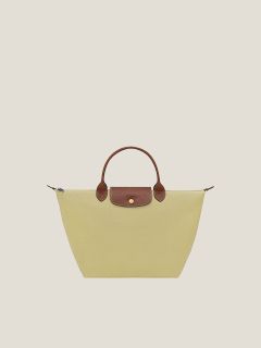 Zwei Handtaschen auf weißem Hintergrund: eine schwarze mit kurzen Henkeln und einem goldenen Knopf, die andere weiße mit kurzen Henkeln, einem goldenen Knopf und einem langen Riemen. Beide Taschen haben eine strukturierte Oberfläche.