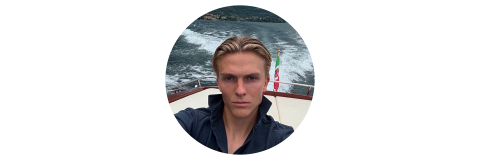 Circular portrait of a woman with slicked-back hair in a dark jacket, stern expression, on a boat with water in the background