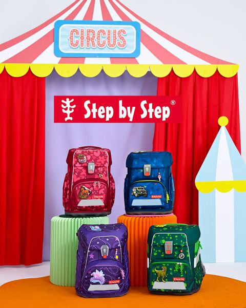 Vor einem Spielzelt sitzen zwei Kinder auf dem Boden, jedes mit einem bunten Rucksack. Links steht der Text „Passt garantiert immer!“. Im Hintergrund sind Regale mit Spielsachen und Deko zu sehen.