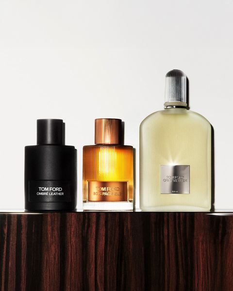 Ein Schwarzweißbild, das einen Mann und eine Frau mit breitkrempigen Hüten zeigt. Sie stehen sich dicht gegenüber. In der unteren linken Ecke befindet sich eine Flasche mit der Aufschrift „Tom Ford Eau d'Ombre Leather“. Der Markenname ist deutlich zu sehen.
