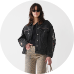 Eine Person mit Sonnenbrille, schwarzer Jacke und Hose mit Leopardenmuster hält eine beige Handtasche. Die Jacke weist gestickte Muster an den Ärmeln und der oberen Vorderseite auf. Sie stehen vor einem schlichten weißen Hintergrund.