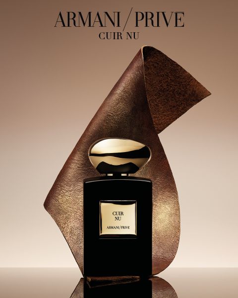 Ein schwarz-goldener Parfümflakon von Armani/Privé „Cuir Nu“ mit einem gewellten Lederblatt im Hintergrund vor einem beigefarbenen Farbverlauf.