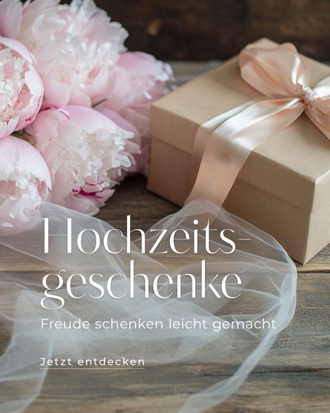 Eine beige Geschenkbox mit Satinband liegt neben rosa Pfingstrosen auf einem Holztisch. Daneben ist weißer Tüll drapiert. Der deutsche Text lautet: „Hochzeitsgeschenke – schenken Freude leicht gemacht. Jetzt entdecken.“.