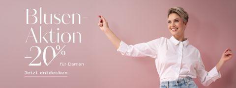 Eine lächelnde Frau in weißer Bluse und hellen Jeans zeigt vor rosa Hintergrund nach oben. Der Text lautet: „Blusen-Aktion -20% für Damen. Jetzt entdecken“ und wirbt mit 20% Rabatt auf Blusen für Damen.
