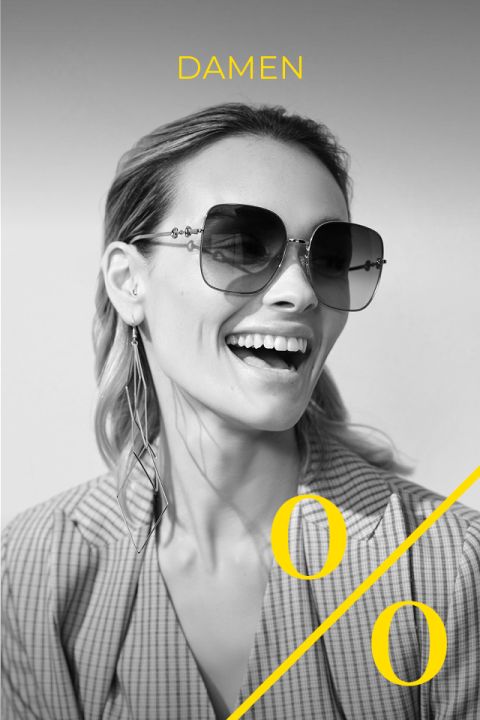 Schwarz-Weiß-Foto einer lächelnden Frau mit großer Sonnenbrille und langen Ohrringen, gekleidet in einen karierten Blazer. Das Wort „DAMEN“ und ein großes gelbes Prozentzeichen sind über das Bild gelegt.