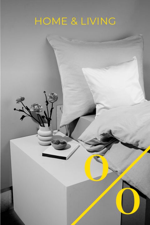 Eine moderne Schlafzimmerszene mit einem Bett, großen und kleinen Kissen, einer Blumenvase, einem Buch und einer Schüssel in Schwarzweiß. Die Worte „HOME & LIVING“ und ein großes gelbes Prozentzeichen sind über das Bild gelegt.