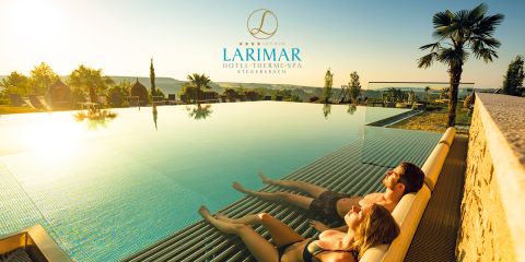Ein Mann und eine Frau entspannen sich auf Liegen in einem Pool bei Sonnenuntergang, mit Blick auf eine malerische Landschaft mit Palmen. Das Logo des Larimar Hotel-Therme-Spa Stegersbach ist über ihnen zu sehen.