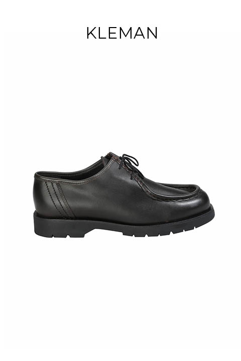 Ein schwarzer Lederschnürschuh mit einer dicken Profilsohle in Profilansicht auf weißem Hintergrund. Der Markenname "KLEMAN" erscheint über dem Schuh.
