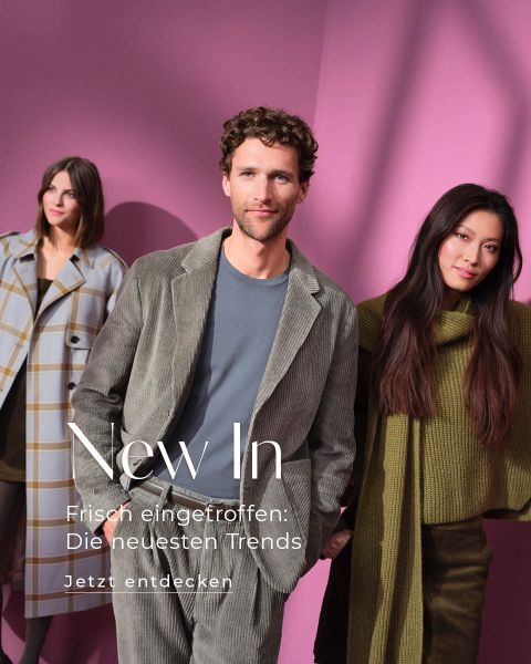 Drei Models posieren in stilvollen Herbstoutfits vor einem rosa Hintergrund. Der Mann im Vordergrund trägt einen grauen Cordanzug, während die Frauen hinter ihm trendige Lagenkleidung in Karo- und Strickstrukturen tragen. Ein deutscher Text überlagert das Bild.