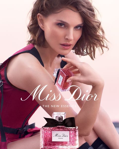 Eine Frau in einem ärmellosen Kleid hält einen rosafarbenen Miss-Dior-Parfümflakon an ihr Gesicht. Ein weiterer Flakon befindet sich im Vordergrund. Der Text lautet "Miss Dior, The New Essence".
