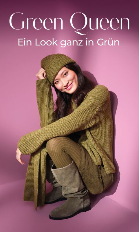 Eine lächelnde Frau in grünem Strickpullover, passender Mütze, olivgrüner Hose und grauen Stiefeln sitzt vor einem rosa Hintergrund. Der Text darüber lautet: "Green Queen - Ein Look ganz in Grün.