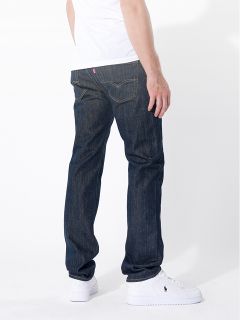 Eine Person, die dunkelblaue Jeans, ein weißes T-Shirt und weiße Turnschuhe trägt, steht mit dem Rücken zur Kamera vor einem schlichten weißen Hintergrund.