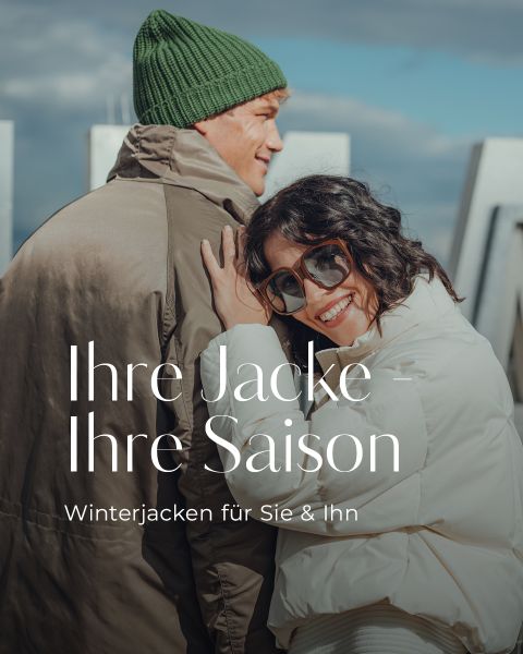Eine lächelnde Frau in einer weißen Winterjacke und mit Sonnenbrille lehnt sich an einen Mann mit grüner Mütze und braunem Mantel. Der Text auf dem Bild lautet: "Ihre Jacke - Ihre Saison. Winterjacken für Sie & Ihn.