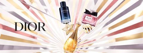 Die Parfümflakons von Dior, darunter Sauvage, J'adore und Miss Dior, sind mit einem goldenen Sternenornament auf einem strahlenden, metallisch gestreiften Hintergrund dargestellt. Das Wort "DIOR" steht auf der linken Seite.