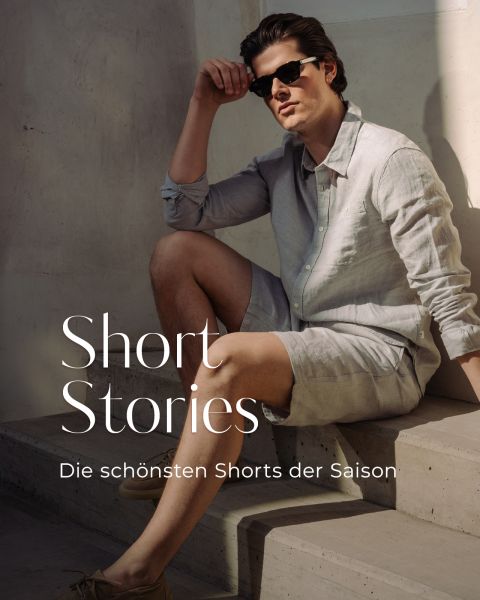 Ein Mann mit Sonnenbrille, hellem Leinenhemd und kurzen Hosen sitzt auf einer Betontreppe. Der Text lautet: "Kurzgeschichten. Die schönsten Shorts der Saison.".
