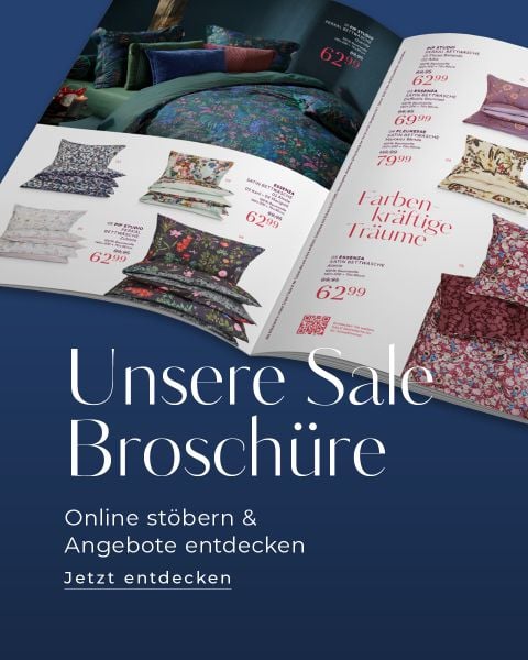 Eine aufgeschlagene Broschüre zeigt bunte Bettwäschesets mit Preisen. Der Text darunter lautet: "Unsere Sale Broschüre. Online stöbern & Angebote entdecken. Jetzt entdecken.