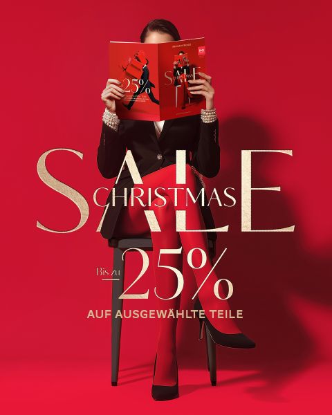 Frau in roter Strumpfhose und schwarzem Blazer sitzt auf einem Stuhl und hält eine rote Zeitschrift in der Hand. Der Text lautet: "CHRISTMAS SALE, Bis zu 25% auf ausgewählte Teile.