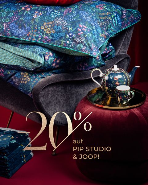 Geblümte Bettwäsche auf einem grauen Stuhl, passende Teekanne auf einer roten Ottomane. Text: "20% auf PIP STUDIO & JOOP!.