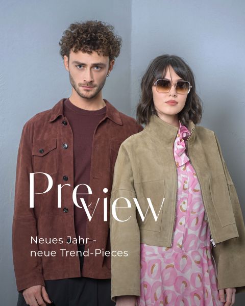 Ein Mann in einer braunen Jacke und eine Frau mit Sonnenbrille, hellbrauner Jacke und rosa Kleid posieren vor einer grauen Wand. Text: "Vorschau Neues Jahr - neue Trend-Pieces".