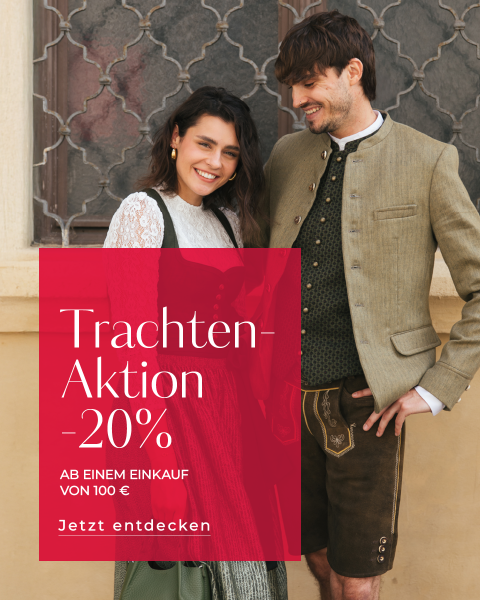 Eine lächelnde Frau in einem grünen Dirndl und ein Mann in traditioneller bayerischer Tracht stehen nebeneinander an einem Fenster. Ein rotes Banner wirbt für einen Rabatt von 20 %.