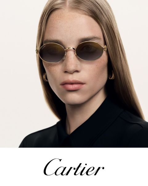 Frau mit glattem Haar, die eine ovale Sonnenbrille und goldene Ohrringe trägt, gekleidet in Schwarz, darunter steht in eleganter Schrift "Cartier".