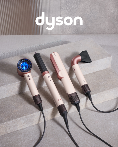 Drei Dyson-Haarstylinggeräte in Pink- und Kupferfarben sind auf Betonstufen aufgereiht, darüber das Dyson-Logo.