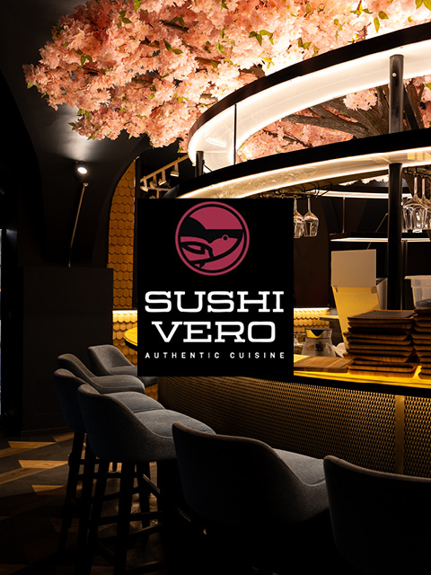 Modernes Sushi-Restaurant mit einer Decke aus Kirschblüten, stilvollen Sitzgelegenheiten und dem Logo von Sushi Vero Authentic Cuisine in der Mitte.
