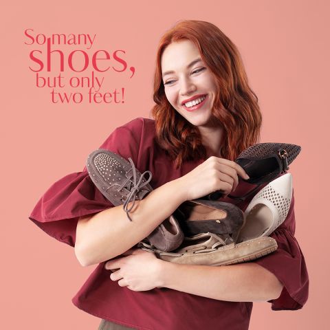 Eine lächelnde Frau mit roten Haaren umarmt mehrere Paar Schuhe; der Text lautet: "So viele Schuhe, aber nur zwei Füße" auf einem rosa Hintergrund.